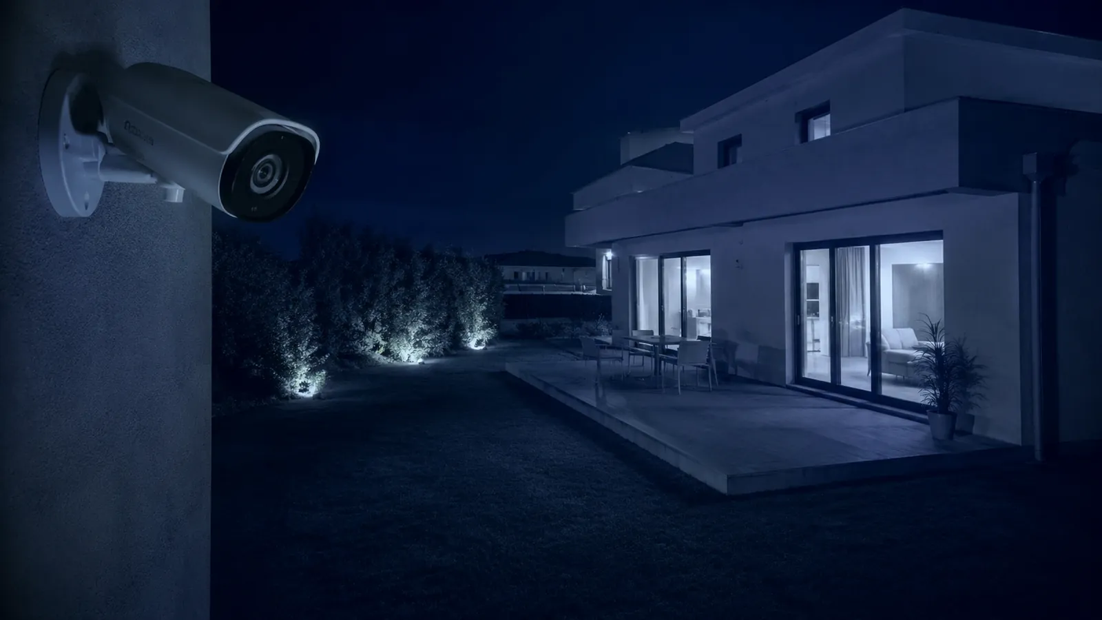 Cámara de seguridad con visión nocturna vigilando una casa moderna de noche